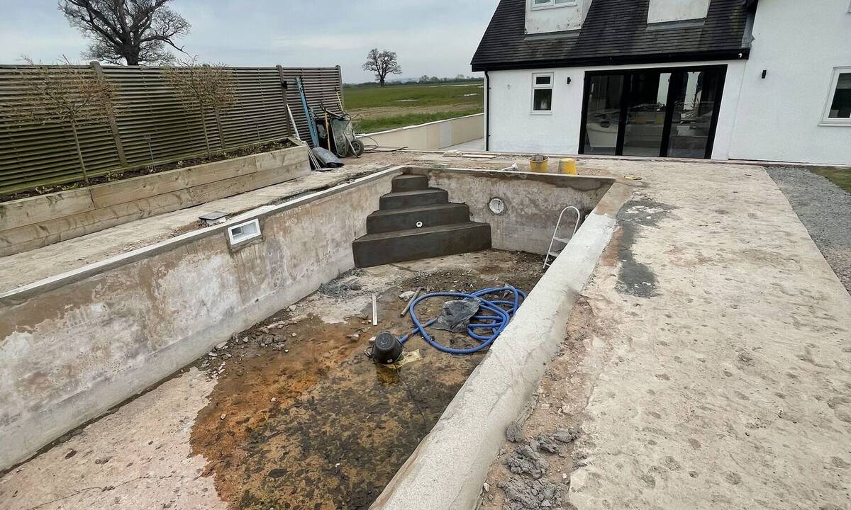 Pool and patio area with steps and structure taking shape