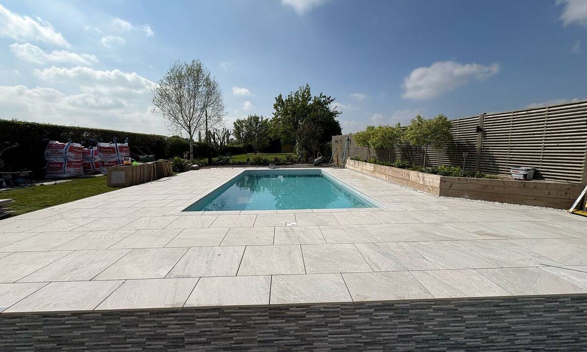 Poolside patio nearing completion with landscaping in place